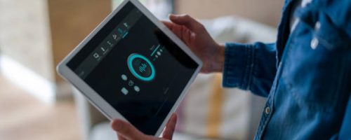 Close-up on a woman controlling the music in her house using a home automation system on a digital tablet - smart home concepts. **DESIGN ON SCREEN WAS MADE FROM SCRATCH BY US**